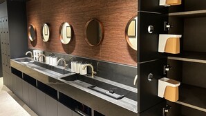 Ein modernes Badezimmer mit einem langen Waschtisch, mehreren Waschbecken und wandmontierten Spiegeln.