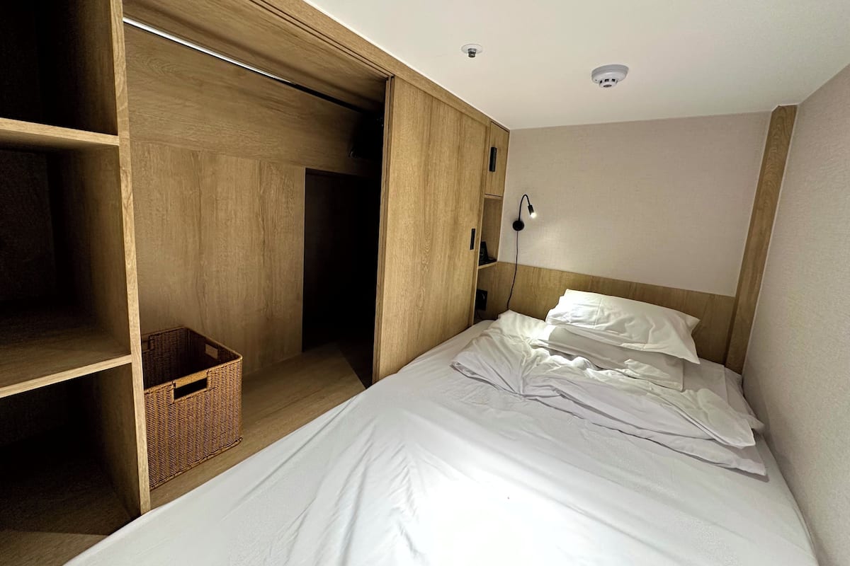 A bedroom with a bed, a wardrobe, and a small wicker basket.
