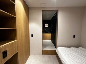 A bedroom with a wooden wardrobe, a mirrored closet door, and a bed.