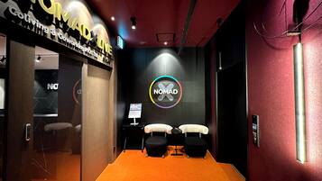 A conference room with an orange carpet, a large NOMAD logo on the wall, and a glass door entrance.