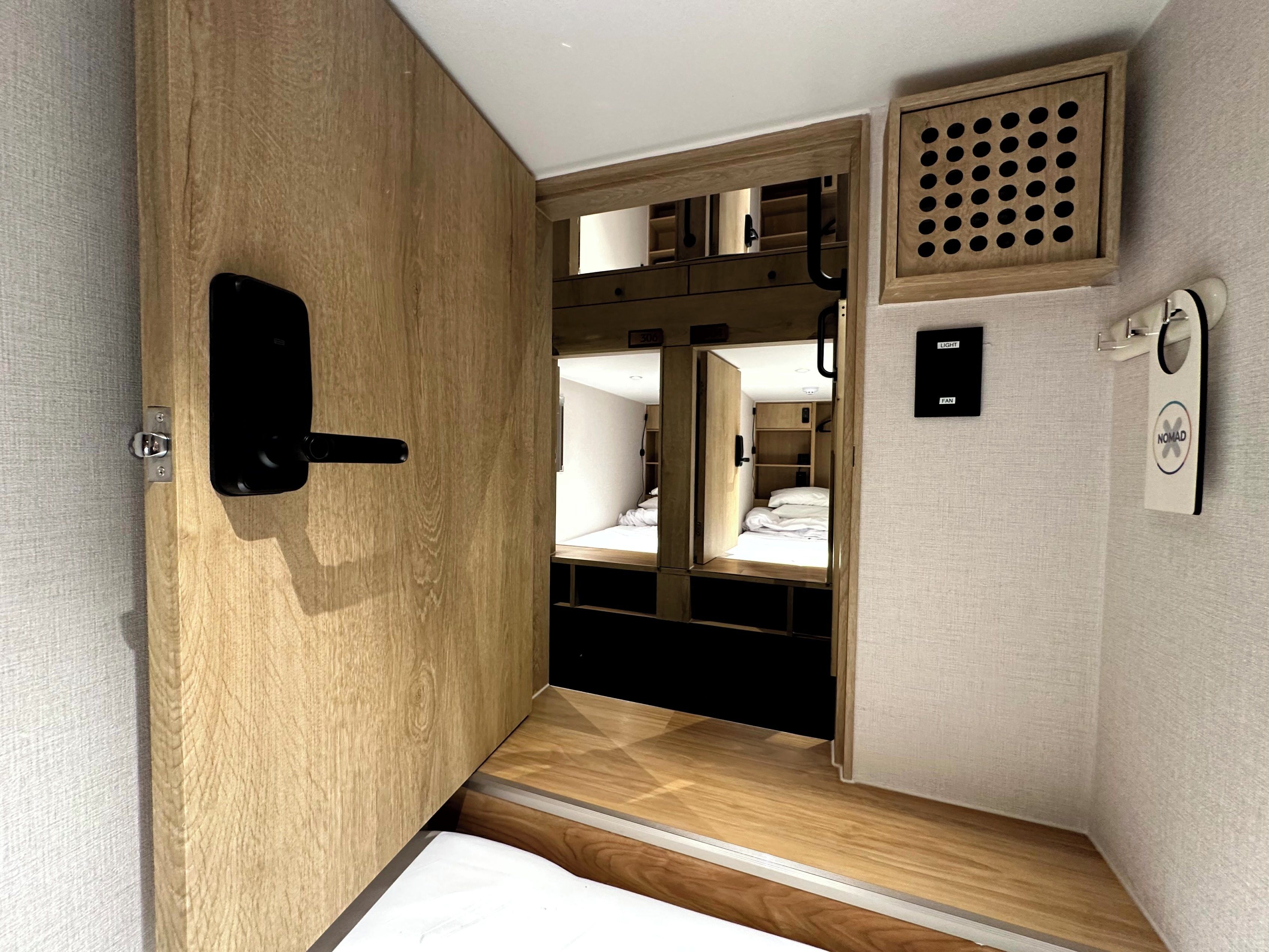 A compact room with a wooden wardrobe, a small bed, and a built-in shelf.