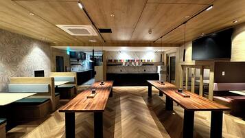 A modern restaurant with wooden flooring, long tables, and booths.