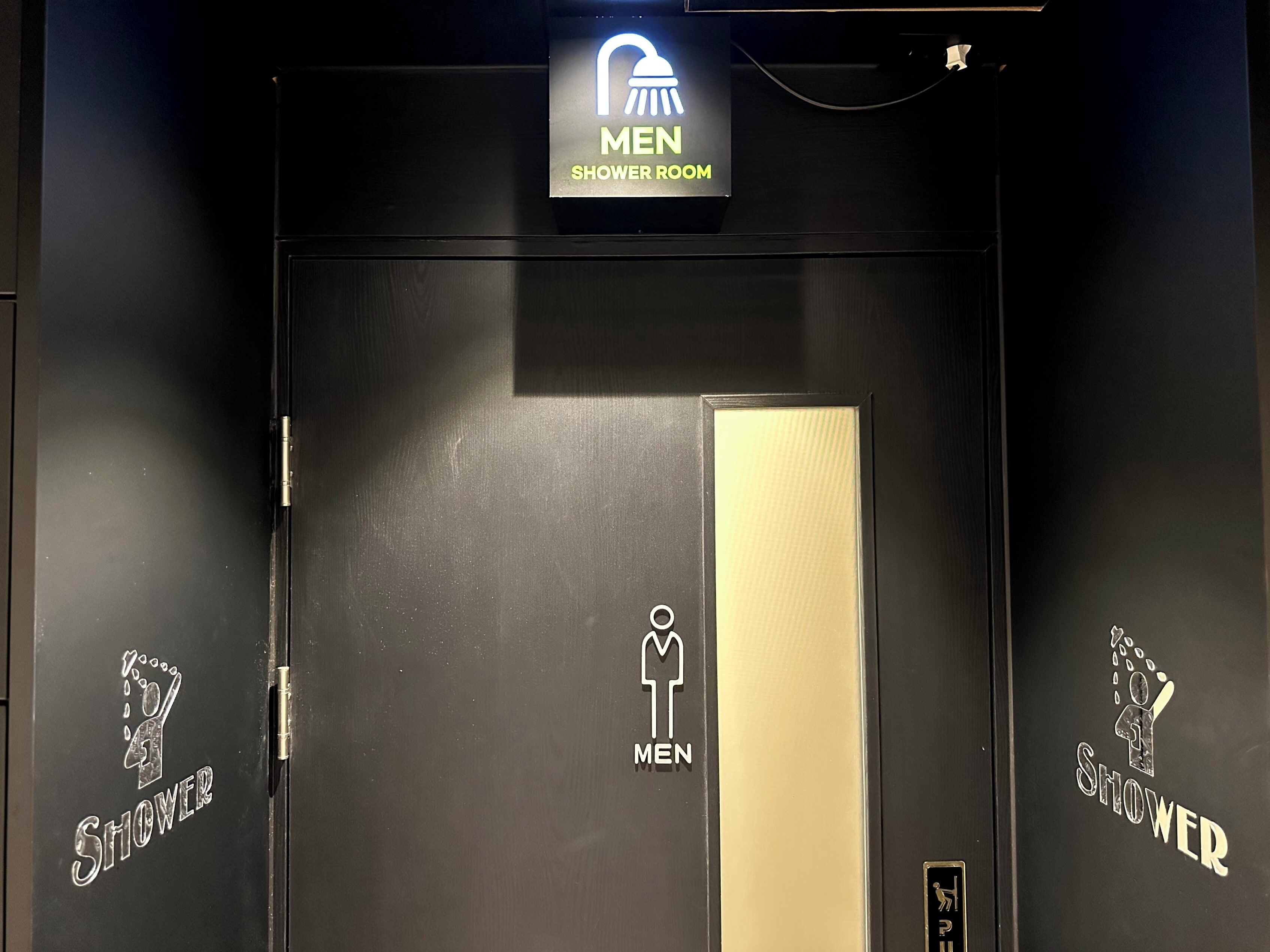 A men's shower room with a sign above the door and symbols on the door indicating it is for men.