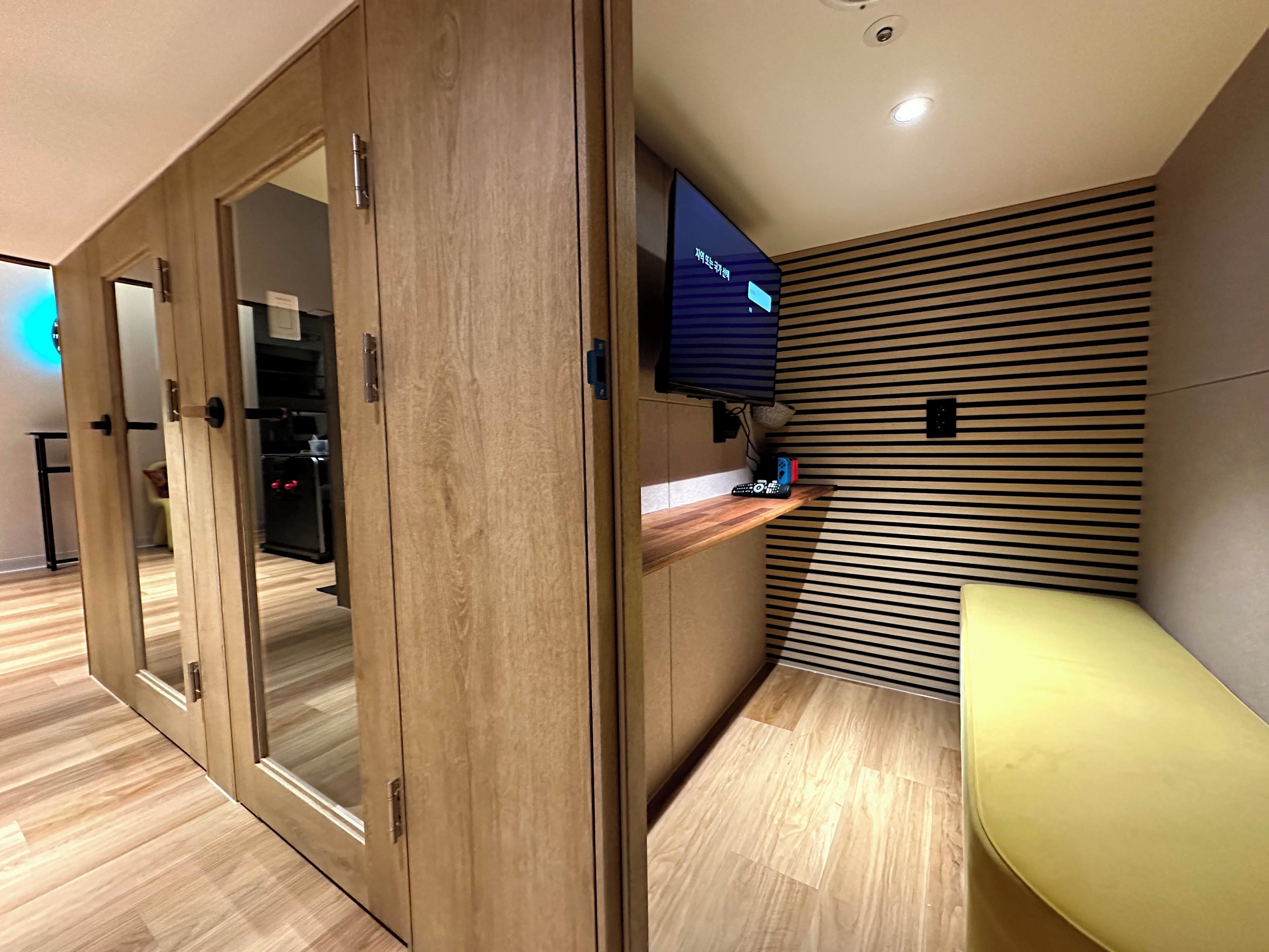 A modern room with wooden flooring, a built-in TV, and a wooden cabinet with glass doors.