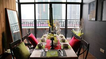 A dining table set with green placemats, white plates, and red cushions.