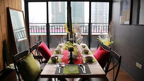 A dining table set with glassware and plates, flanked by chairs with red cushions, in a room with large windows and a balcony view. - Shengshi Hotel (Zengcheng Donghuicheng Wanda Store) (Guangzhou)
