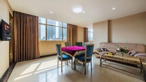 A hotel room with a dining table, chairs, a sofa, and a TV mounted on the wall. - Shengshi Hotel (Zengcheng Donghuicheng Wanda Store) (Guangzhou)