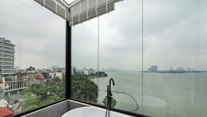 Une salle de bain moderne avec une grande baignoire, une vue sur une rivière et un paysage urbain en arrière-plan.
