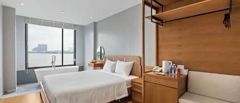 Ein modernes Hotelzimmer mit einem großen Bett, Holzmöbeln, Blick auf die Stadt und einer Badewanne.