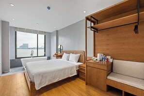 A modern hotel room with a large bed, wooden furniture, a view of the city, and a bathtub. - Lakeview Residence (Hanoi)