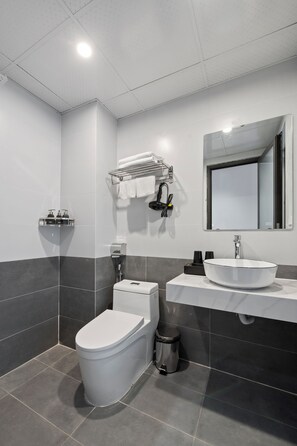 A modern bathroom with a white toilet, a sink with a mirror, and a towel rack. - Lakeview Residence (Hanoi)