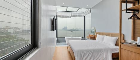 Quarto moderno com uma janela grande, banheira, cama e mesa de cabeceira de madeira.