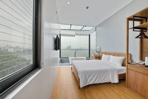 A modern bedroom with a large window, a bathtub, a bed, and a wooden nightstand. - Lakeview Residence (Hanoi)