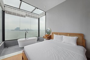 Une chambre d’hôtel moderne avec un grand lit, une baignoire et une vue sur l’eau.