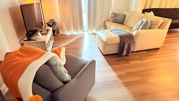 A modern living room with a sofa, a couch, a TV, and a lamp.