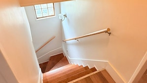 A staircase with wooden steps and a handrail, leading to a landing with a small window.