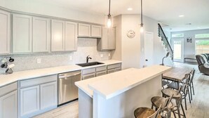 A modern kitchen with white cabinetry, a large island, and pendant lighting. - 3BD Houston Home: Fenced Yard & Minutes to Downtown Houston (Houston)