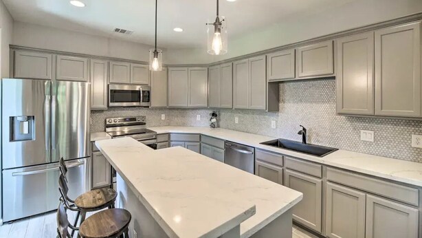 A modern kitchen with stainless steel appliances, a marble countertop, and pendant lighting. - 3BD Houston Home: Fenced Yard & Minutes to Downtown Houston (Houston)