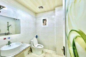 Een badkamer met een wastafel, toilet, spiegel en een klein fotolijstje aan de muur.