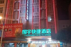 A hotel with a neon sign, multiple floors, and a visible entrance. - Jingxi Guoyu Convenience Hotel (Jingxi)