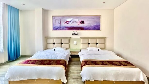 A hotel room with two beds, a large painting on the wall, and a window with blue curtains. - Jingxi Guoyu Convenience Hotel (Jingxi)