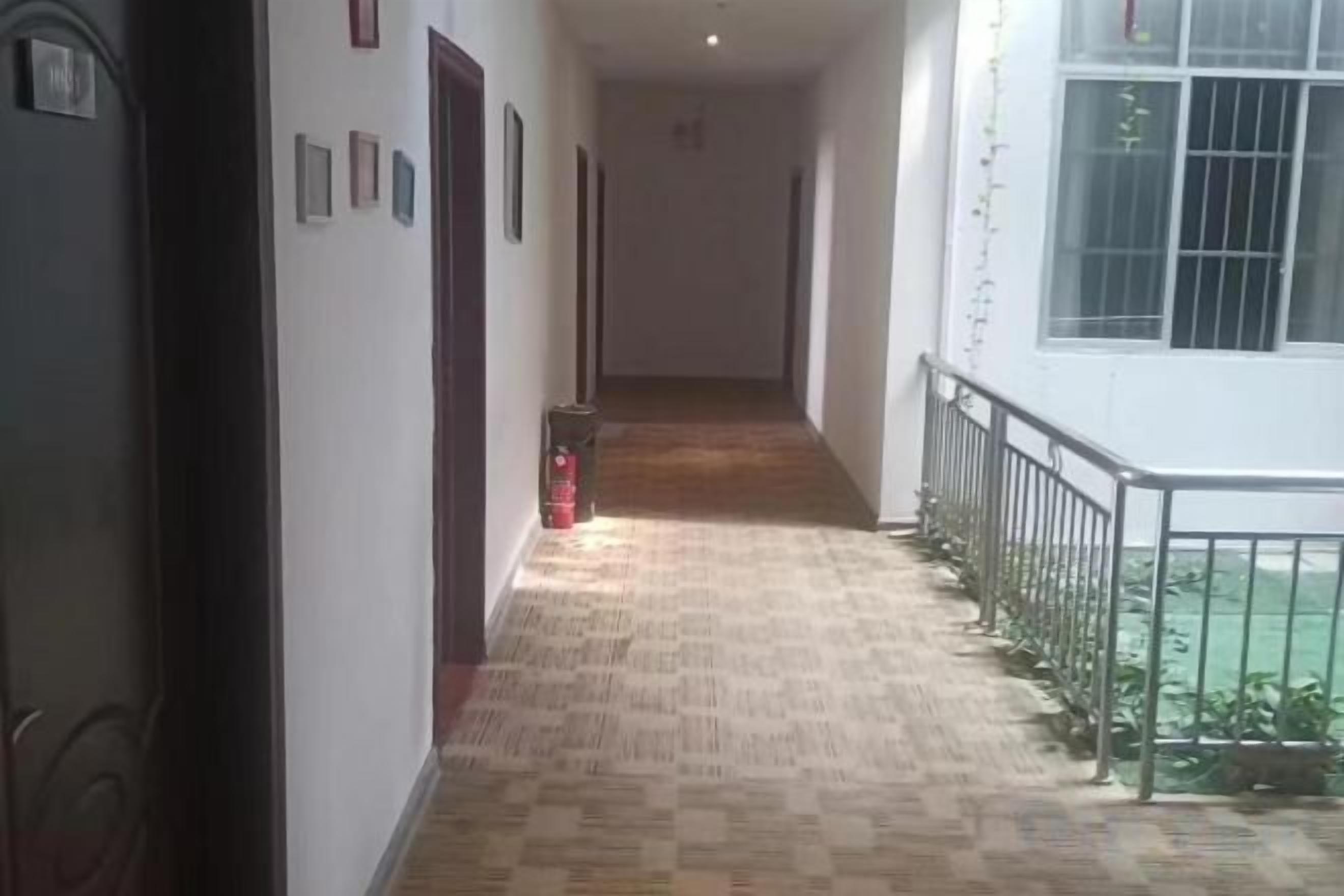 Un pasillo con piso estampado, un extintor y una barandilla a la derecha.