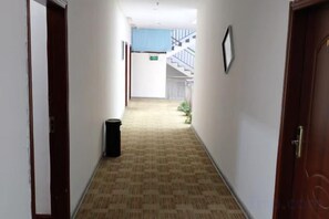 A hotel hallway with carpeted flooring, a trash bin, and a staircase in the background. - Jingxi Guoyu Convenience Hotel (Jingxi)