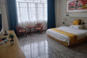 Habitació d'hotel amb llit, escriptori, dues cadires, finestra amb cortines i un quadre a la paret.