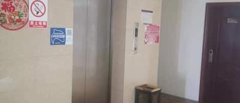 Ascensor, una puerta y un contenedor de basura en un pasillo.