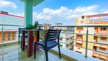 A balcony with a chair, a small table, and a potted plant.
