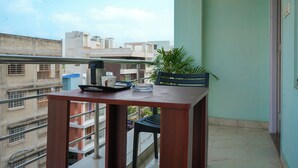 Ein Balkon mit Tisch, einem Blumentopf und Blick auf umliegende Gebäude.