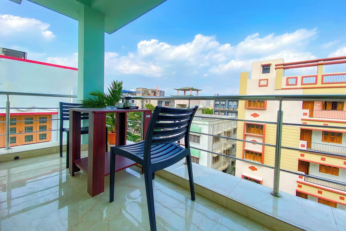 A balcony with a chair, a small table, and a potted plant.