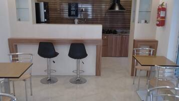 A modern kitchen with a central island, two bar stools, and a fire extinguisher on the wall.