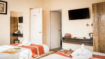A hotel room with two beds, a TV, a wooden desk, and a door leading to another room.