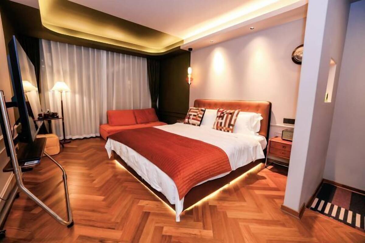 Una habitación de hotel moderna con una cama grande, un escritorio, una silla y una lámpara.