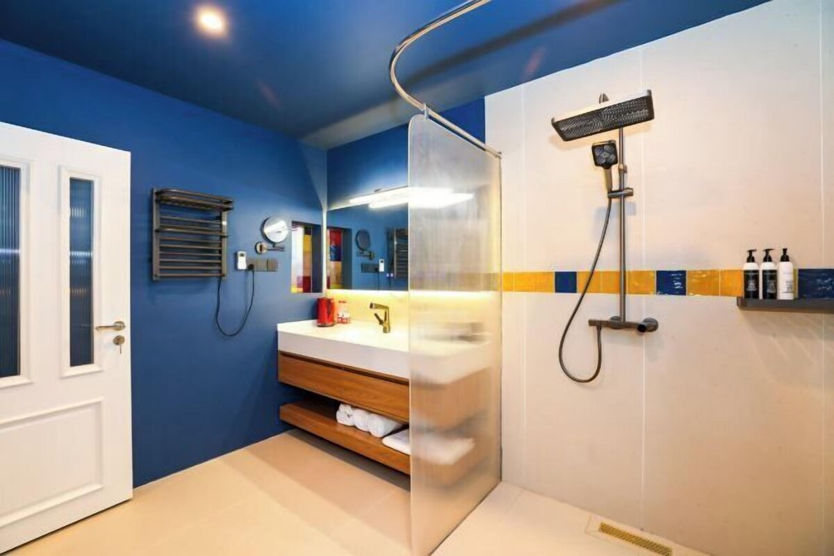 A bathroom with a shower, a sink, a mirror, and a towel rack.