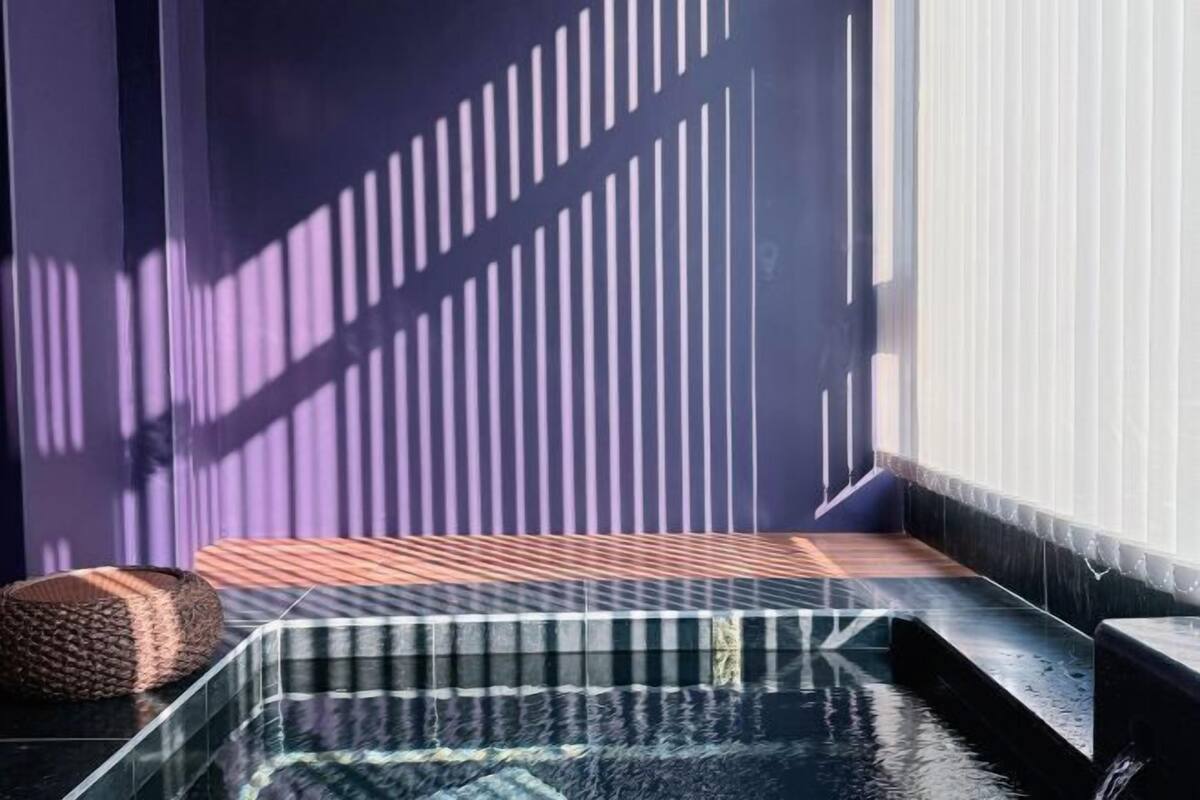 Un área de spa con un jacuzzi envuelto en vidrio, un banco de madera y una alfombra texturizada.