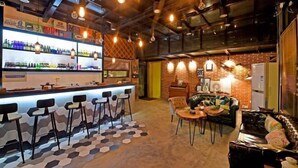 A bar area with a counter, stools, and a seating area with a couch and tables. - L.A.B. Hot Spring Guesthouse, Tangshan, Nanjing (Nanjing)
