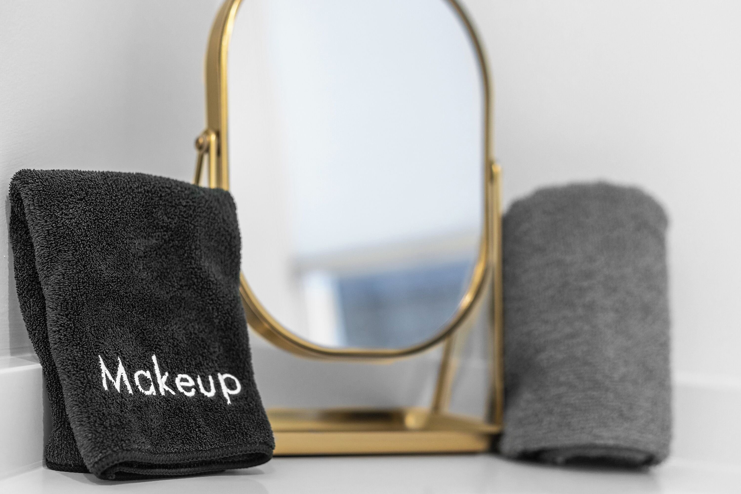Un bagno con uno specchio dalla cornice dorata e due asciugamani, uno dei quali con l'etichetta 'Makeup'.