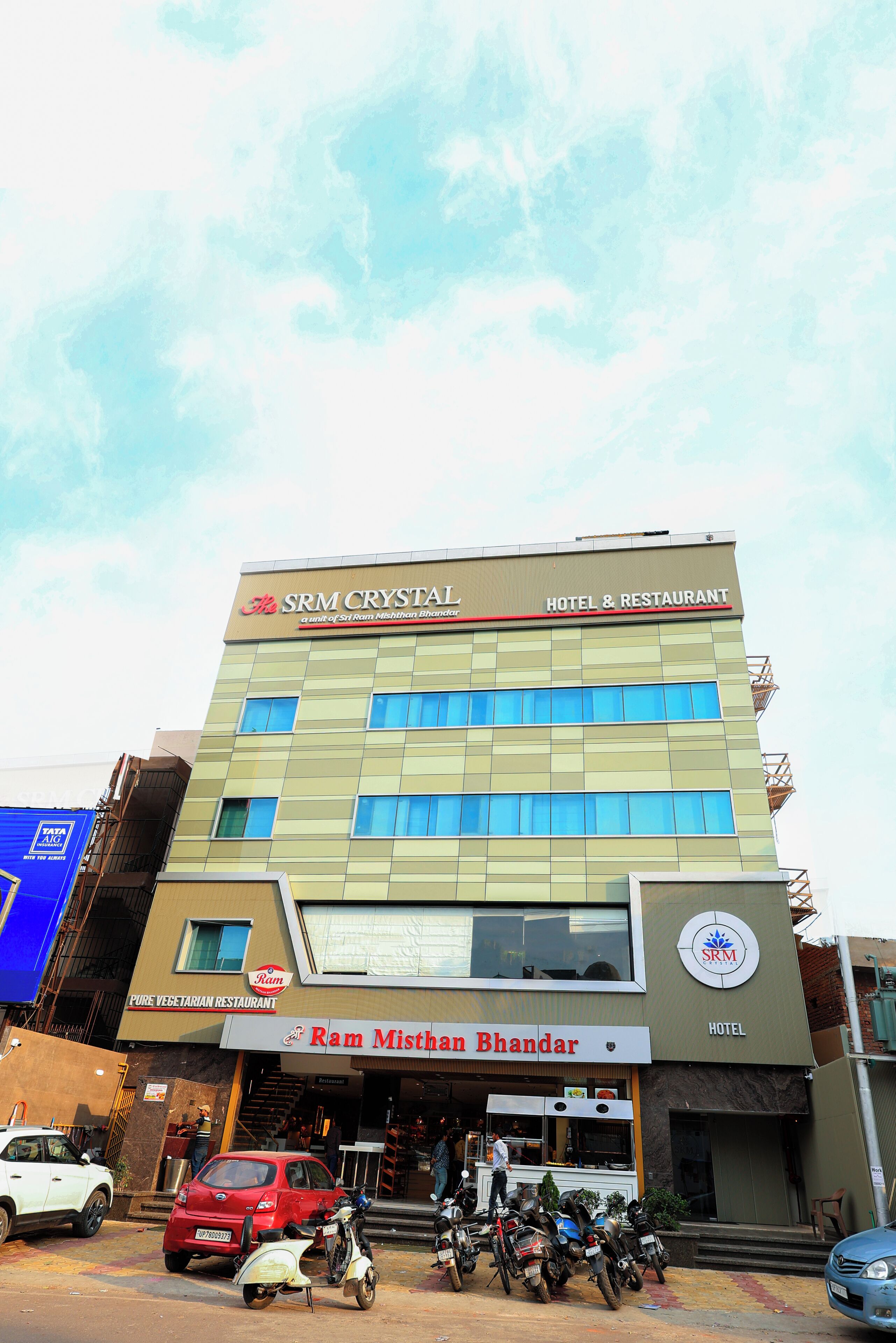 Een meerhoog gebouw met borden voor SRM Crystal Hotel & Restaurant en Ram Mishthan Bhandar.