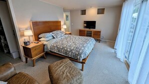 Quarto de hotel com cama, mesas de cabeceira, televisão e janela com cortinas.