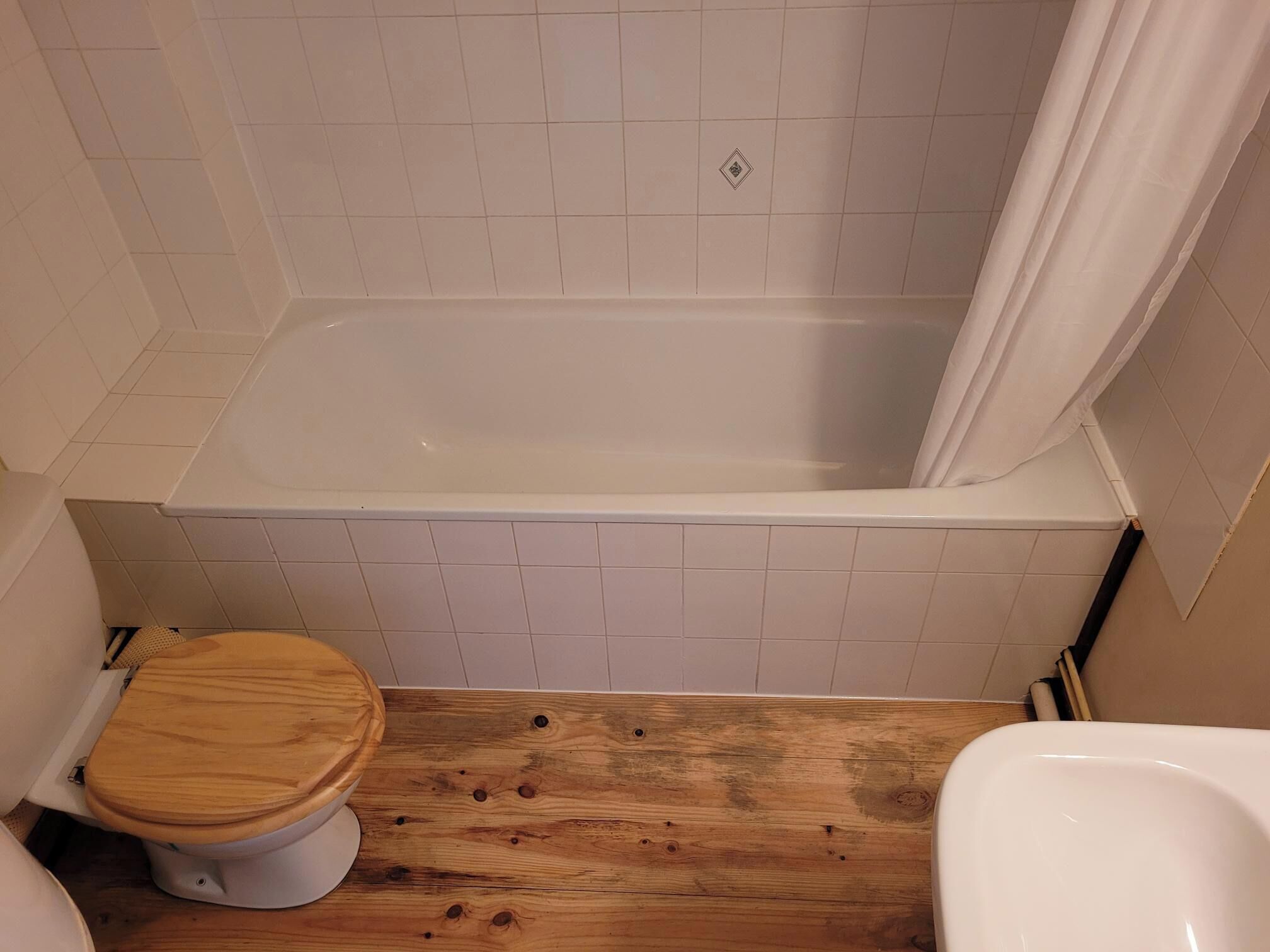 Un baño con bañera, inodoro y cortina de ducha.