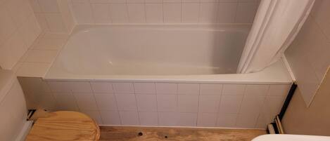 Un baño con bañera, inodoro y cortina de ducha.