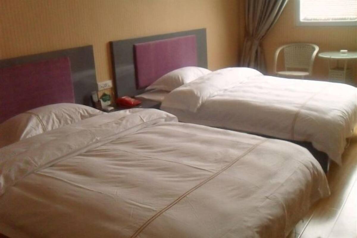 A hotel room with two beds, a small table, and a chair.