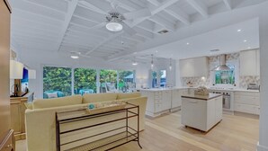 A spacious living area with a sofa, a coffee table, and a kitchen with white cabinets and a central island. - **SOUTHERN STAR @ THE MEADOWS** Home & Pool + Last Key White Glove Service... (Key West)