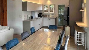 Una cocina moderna con armarios blancos, una mesa de comedor de madera y sillas azules.