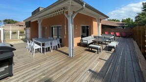 Un patio cubierto con mesa y sillas, una parrilla y una terraza de madera.