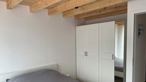 Un dormitorio con cama, armario blanco y vigas de madera en el techo.