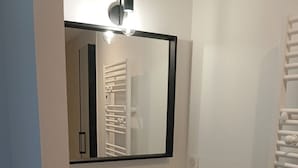Un baño con un lavamanos blanco, un espejo y un toallero.