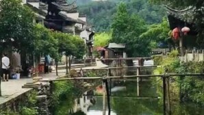 Ein traditioneller chinesischer Innenhof mit Wasserspiel, umgeben von üppiger Vegetation und traditioneller Architektur.